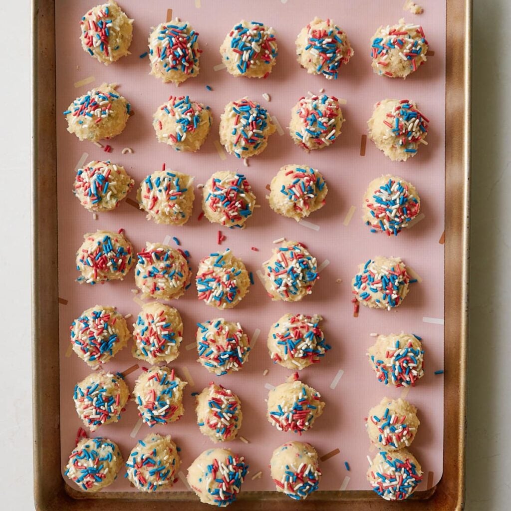 Cookie dough balls lined up on a baking tray for Sourdough Sprinkle Cookies.