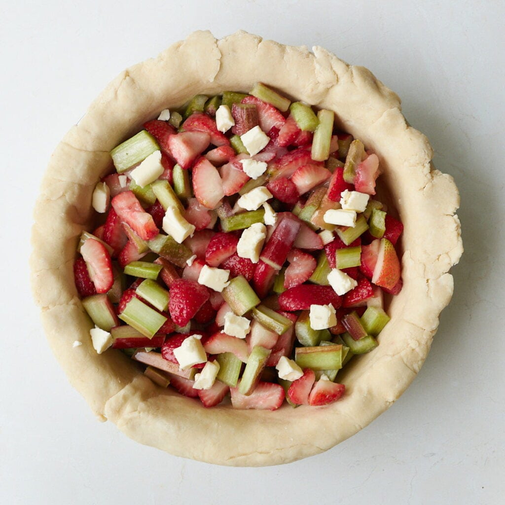 strawberry rhubarb filling with butter on top in a sourdough pie crust.