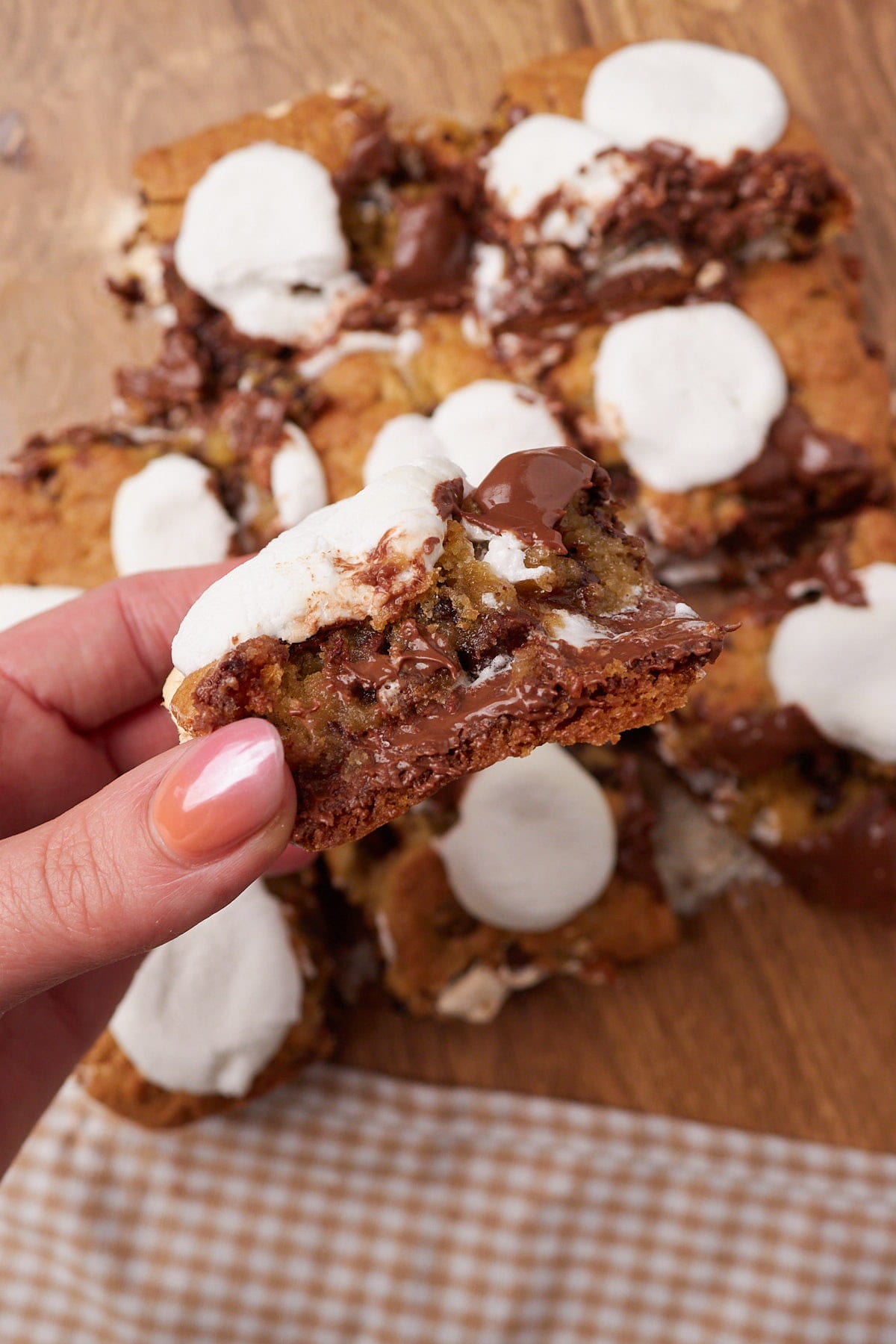 A hand holding a square of the Sourdough S'mores Cookie Bars so you can see the layers inside.