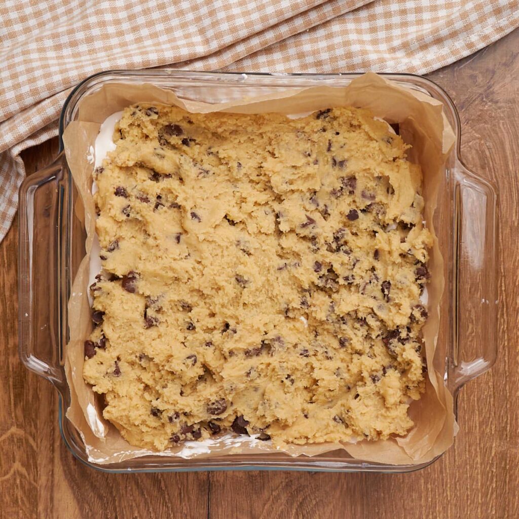 Sourdough Chocolate Chip Cookie dough layer added to the s'mores cookie bars in an 8x8 pan lined with parchment paper.