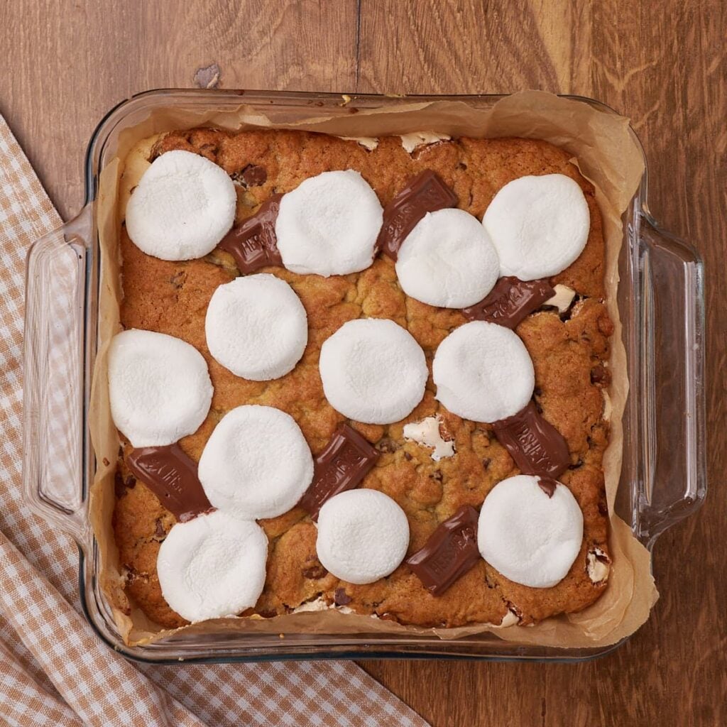 Freshly baked Sourdough S'more Cookie Bars in an 8x8 pan with melted marshmallows and chocolate squares on top.