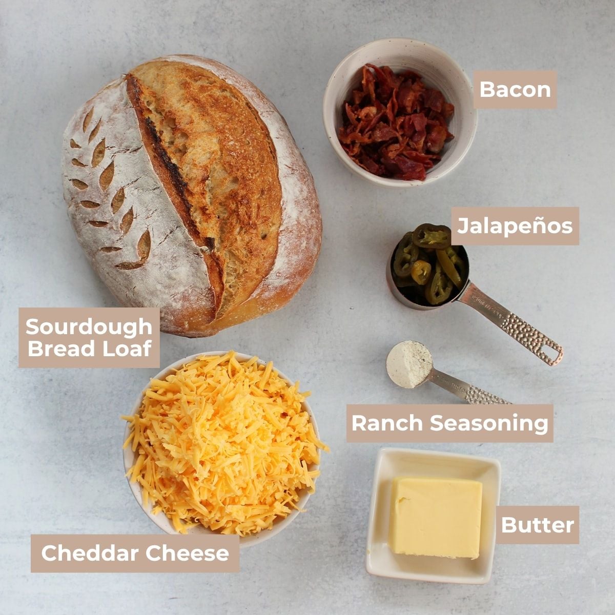 Ingredients for Jalapeno Cheddar Bacon Pull Apart Bread on a grey background.