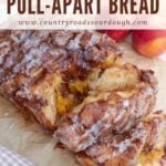 Sourdough Peach Pull-Apart Bread on parchment paper next to three peaches.