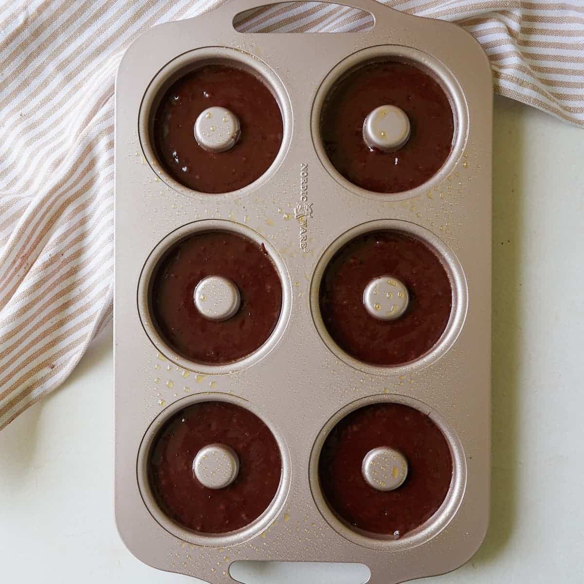 Sourdough chocolate donut batter in a greased donut pan.