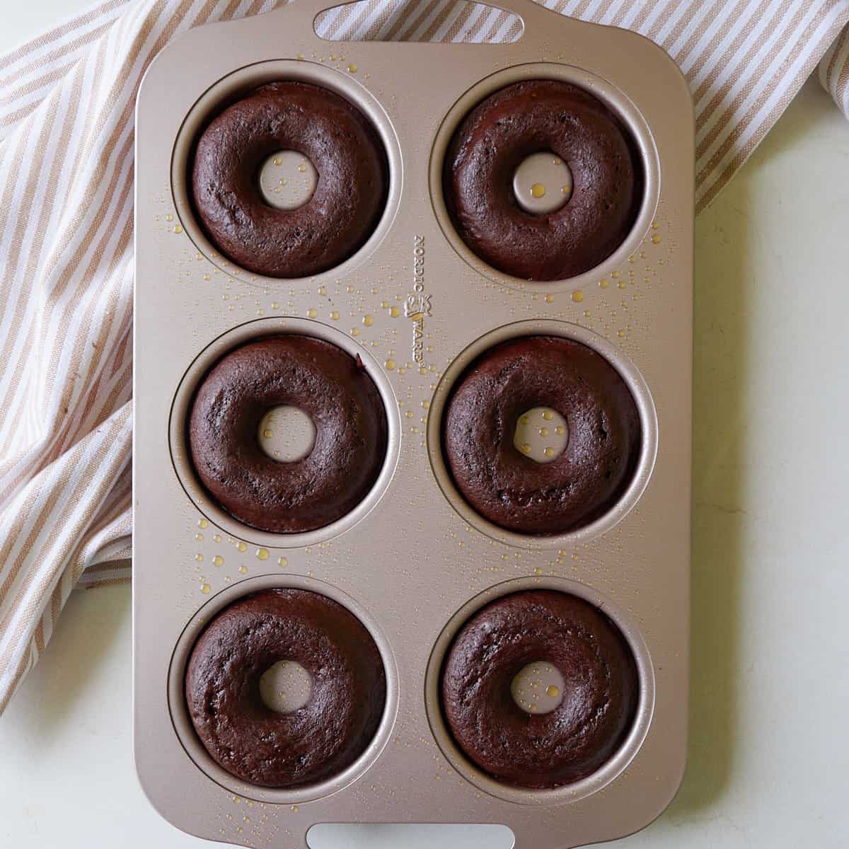 Sourdough chocolate donuts in a donut pan after baking.
