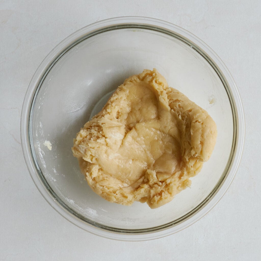 Shortbread crust dough for Sourdough Peach Crumble Cheesecake Bars mixed together in a clear bowl.