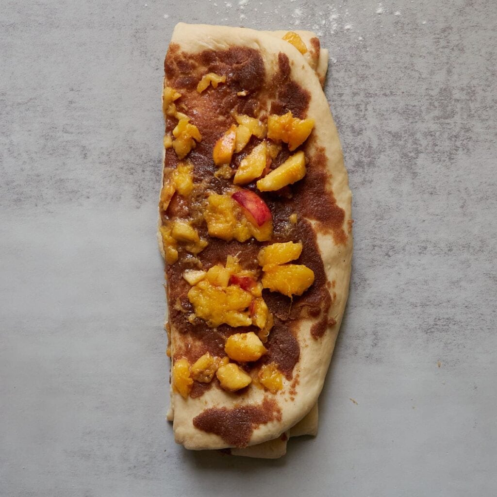 Three slices of dough with filling stacked on top of each other for Sourdough Peach Pull-Apart Bread.