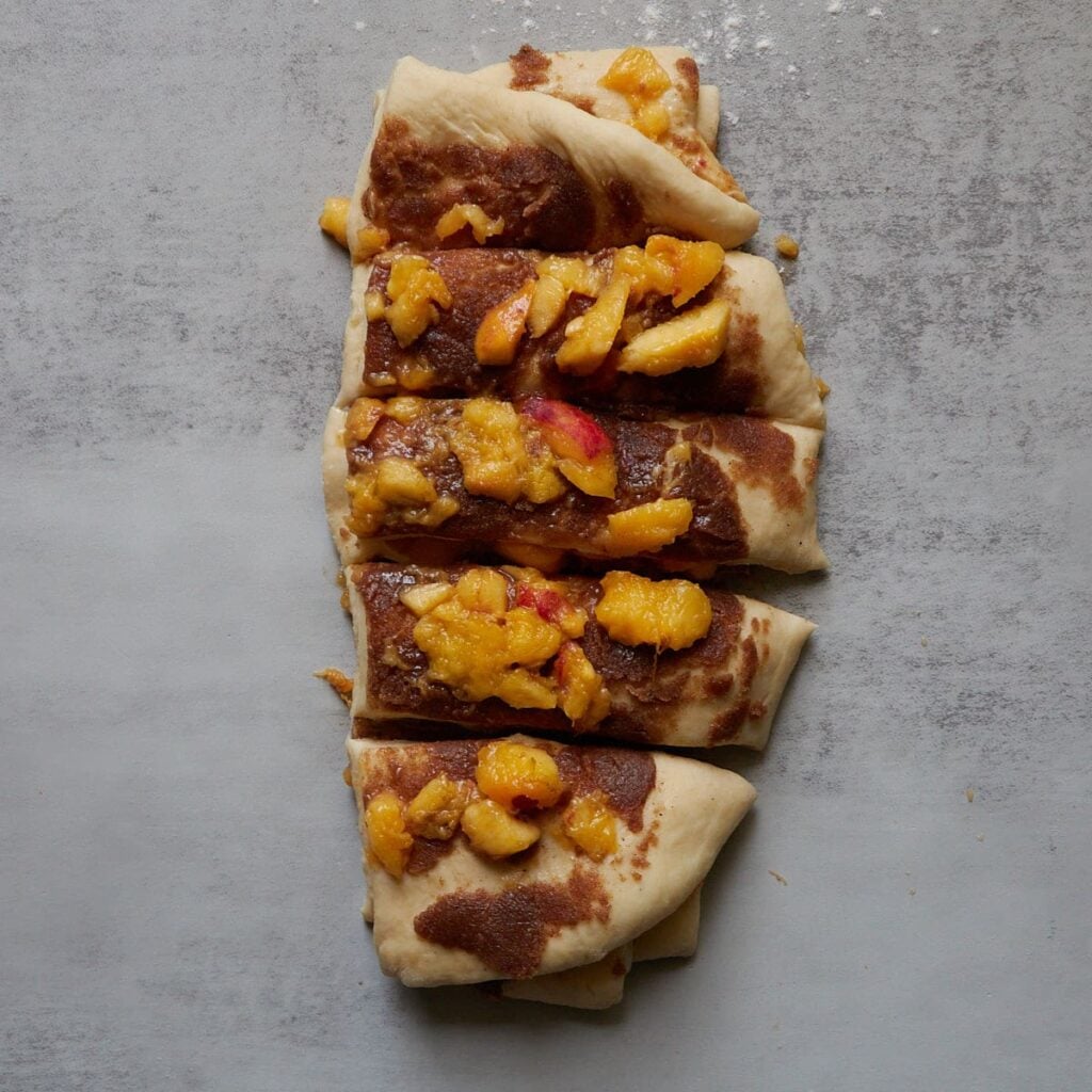 Dough stacked on top of each other and cut into 5 pieces for shaping Sourdough Peach Pull-Apart Bread.