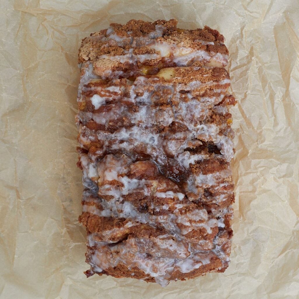 Glaze added on top of freshly baked Sourdough Peach Pull-Apart Bread on parchment paper.