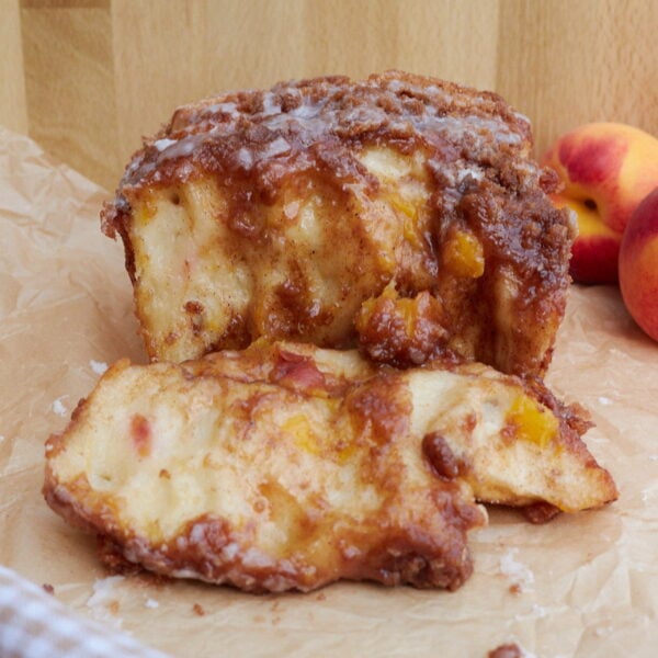 Sourdough Peach Pull-Apart Bread on brown parchment paper with a piece pulled off.