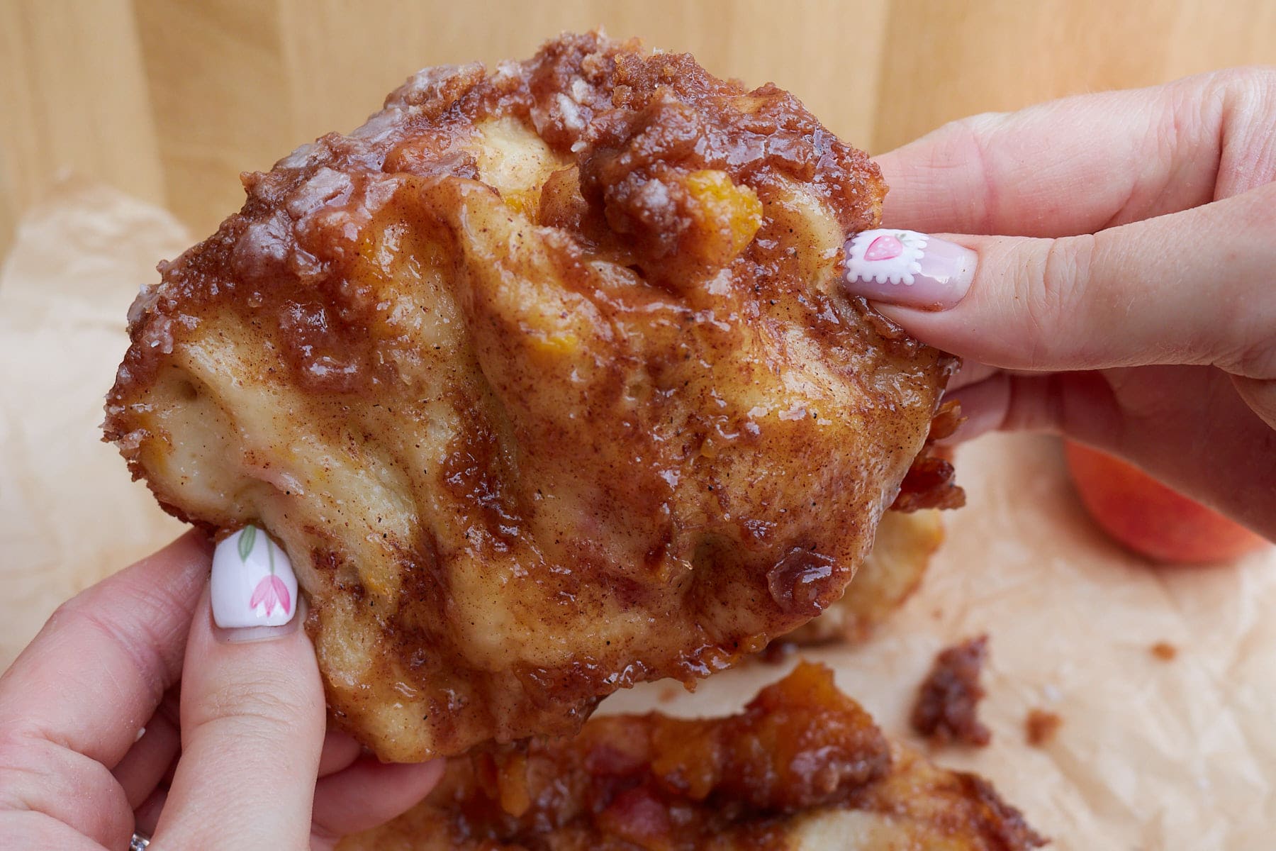 A hand holding a piece of Sourdough Peach Pull-Apart Bread.