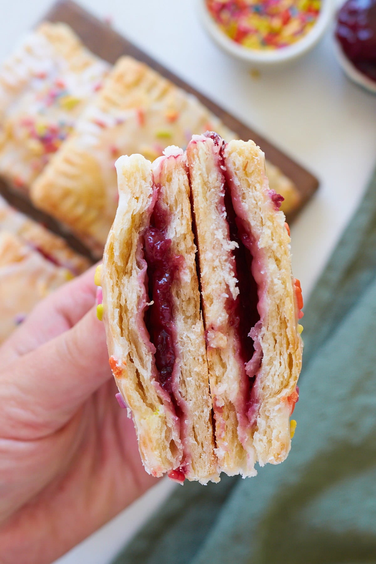 A hand holding a Sourdough Pop Tart cut in half so you can see the jam filling.