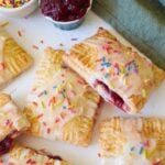 Sourdough Pop Tarts with Icing and sprinkles on a white background with sprinkles scattered around.