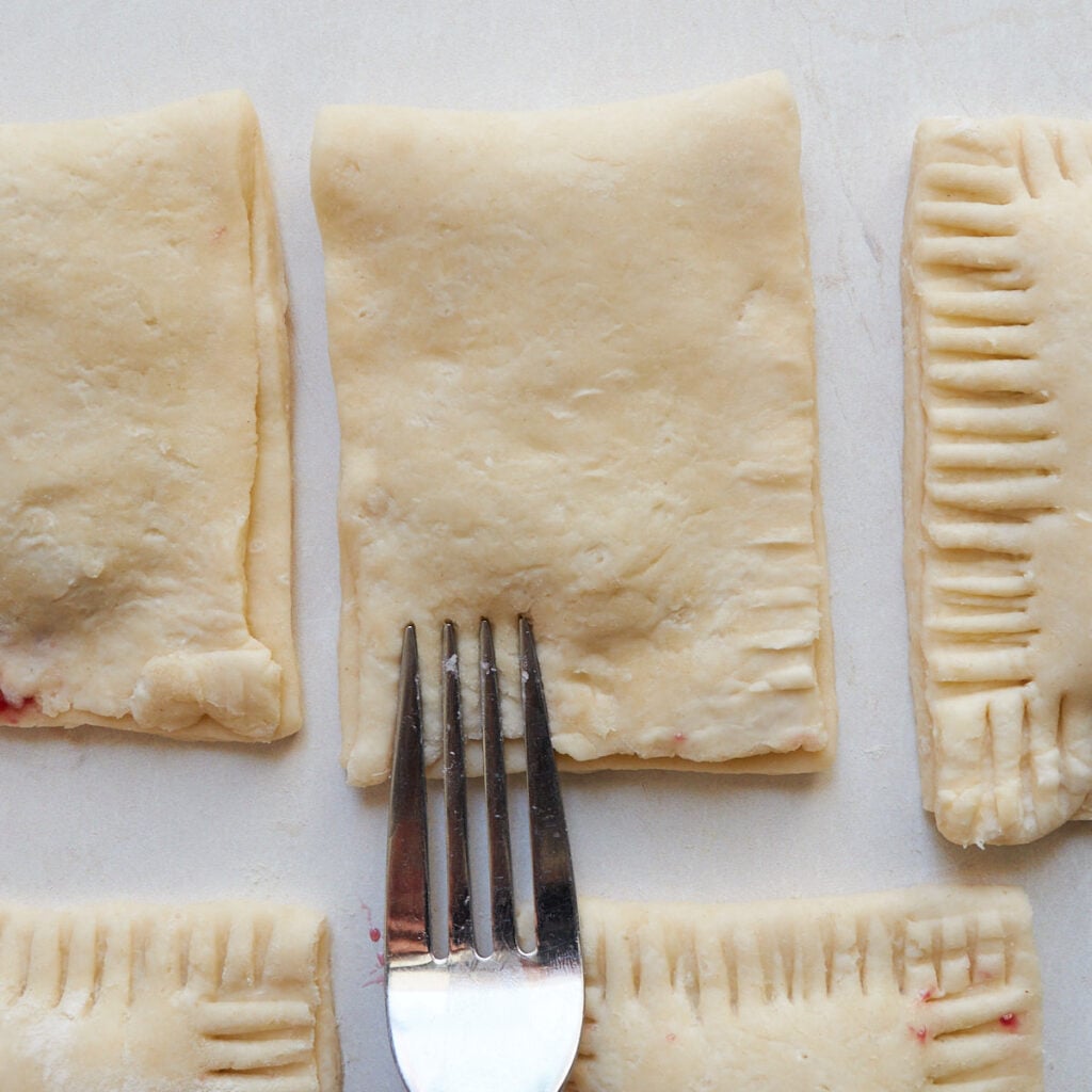 A fork sealing and crimping the edges of the sourdough pop tarts.