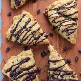 Chocolate Chip Sourdough Scones on a wooden cutting board with chocolate chips scattered around,