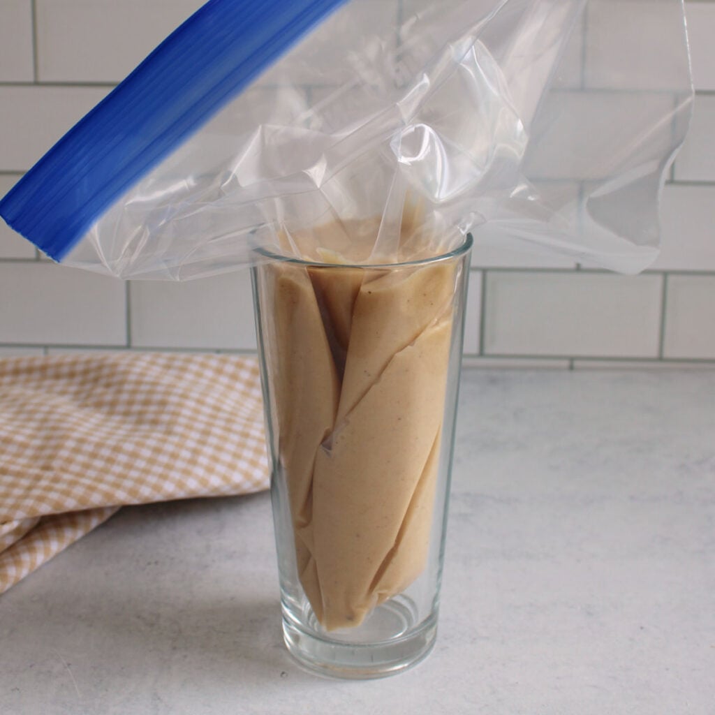 Batter for sourdough discard donuts in a ziplock bag sitting in a large cup.