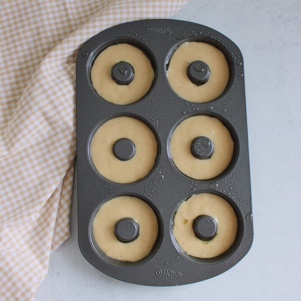 Batter for sourdough discard donuts in a donut pan before baking.