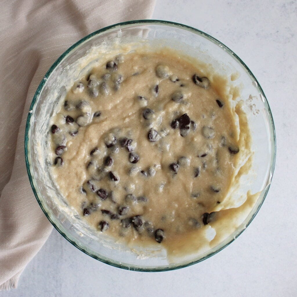 Chocolate chips folded into the batter for Chocolate Chip Sourdough Muffins in a clear bowl.
