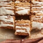 Sourdough Pumpkin Coffee Cake sliced into squares on parchment paper with a wooden handle serving spatula.