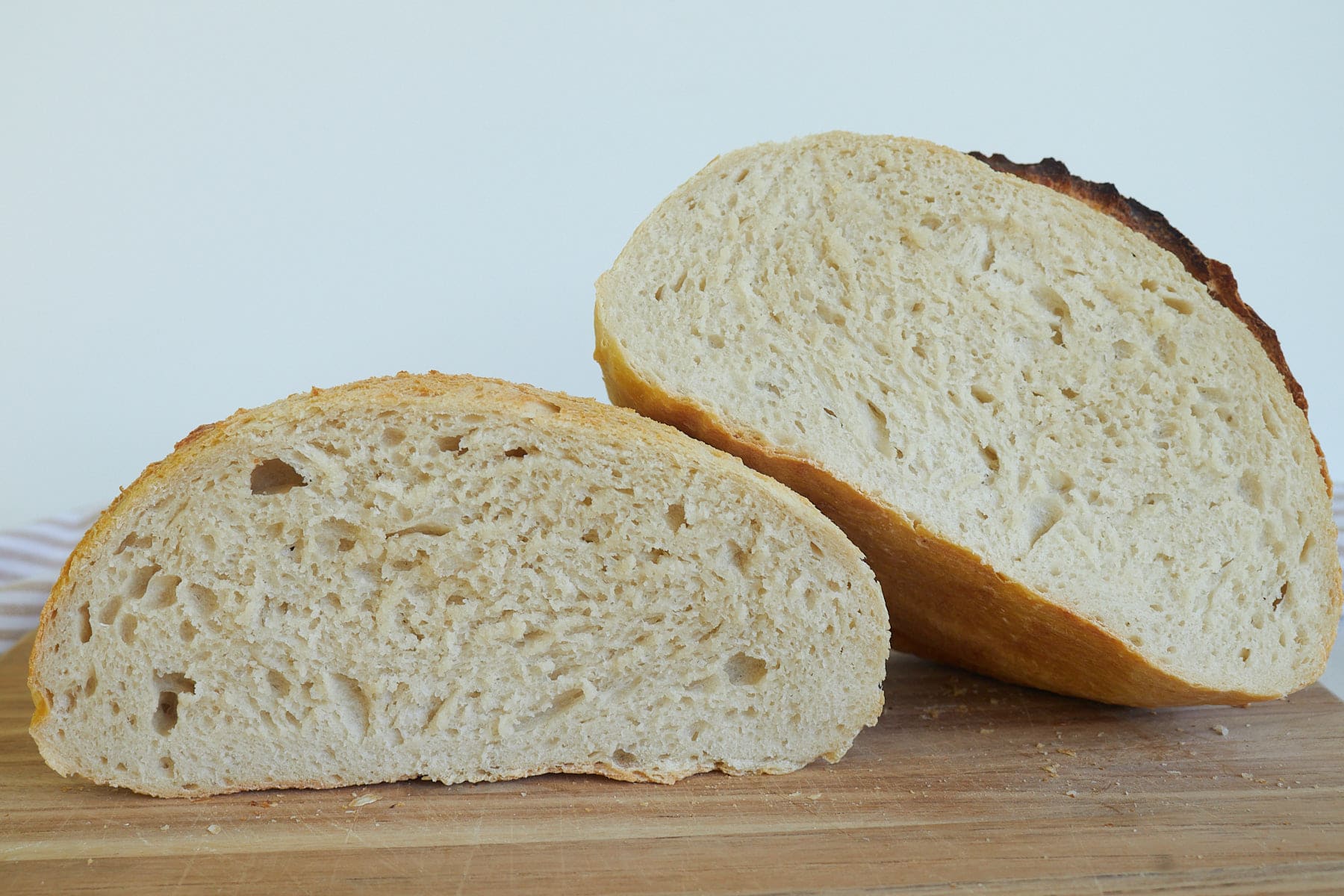 Loaf of Sourdough Discard Bread Sliced in half on a wooden cutting board.