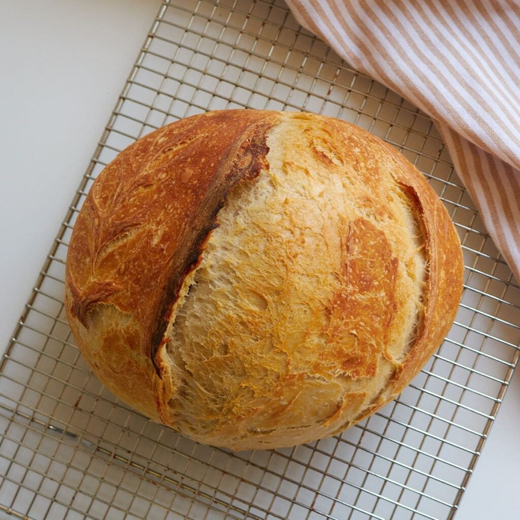 A loaf of sourdough discard bread on a wire cooling rack.