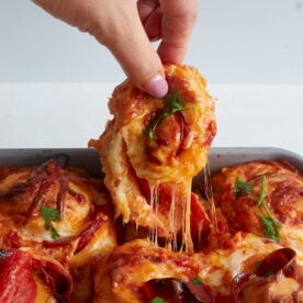 A hand pulling a sourdough pizza roll up from out of the 9x13 pan.
