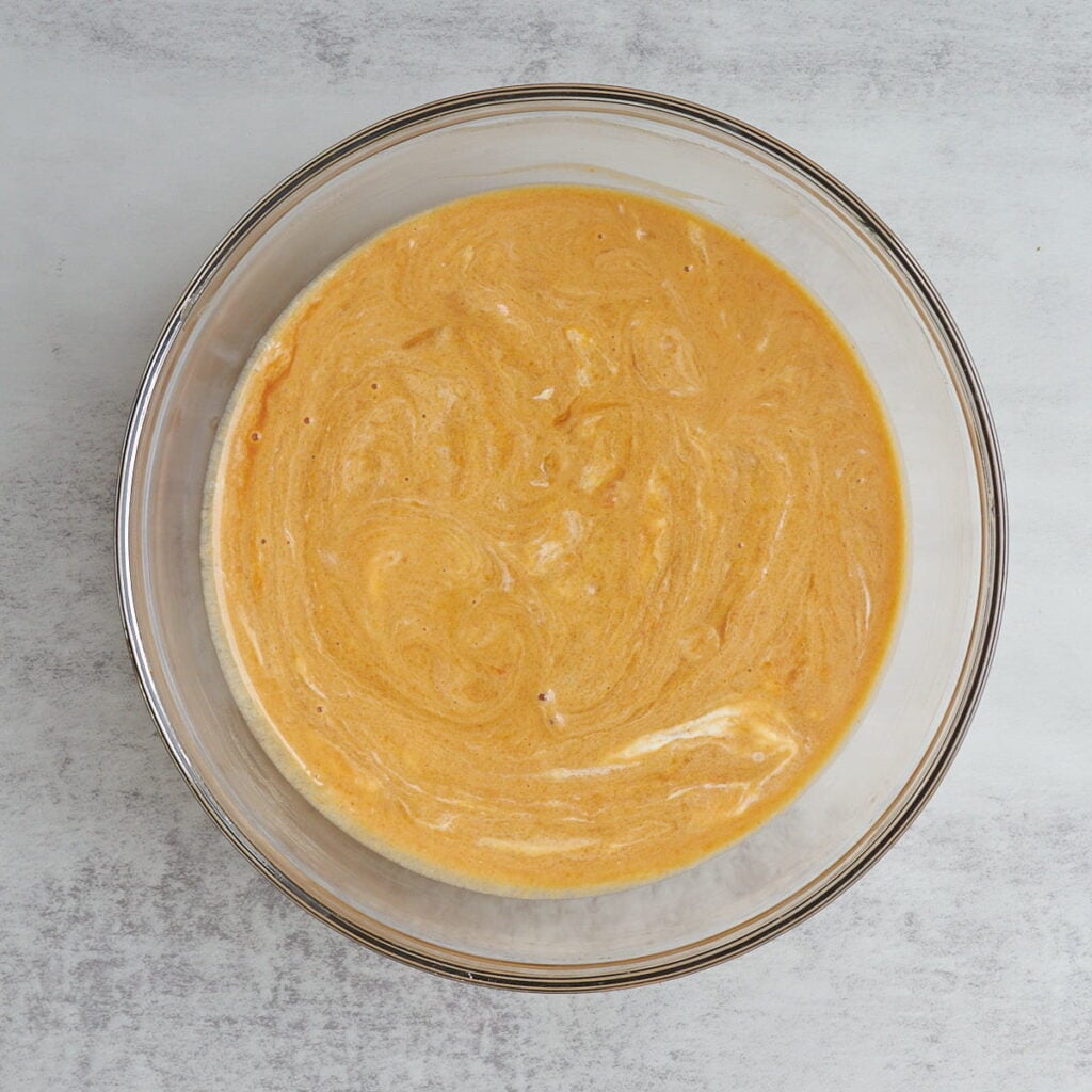 Wet ingredients for sourdough pumpkin coffee cake in a clear bowl.