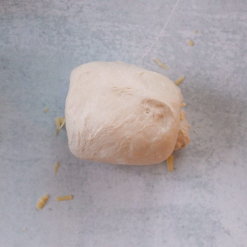 Shaping sourdough mini bread loaves dough with cheddar and jalapeños.