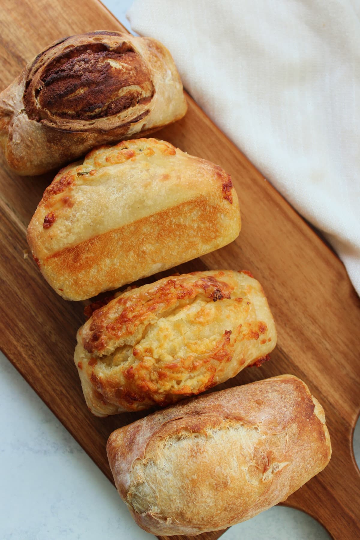 4 Sourdough Mini Bread Loaves on a wooden board.