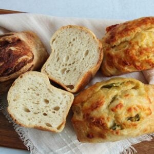 Sourdough mini loaves on a wooden board with one loaf sliced in half.