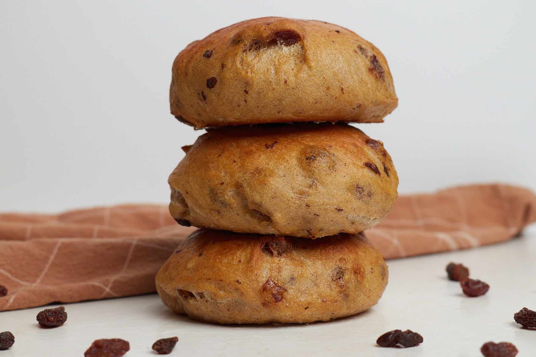 Three cinnamon raisin sourdough bagels stacked on top of each other.