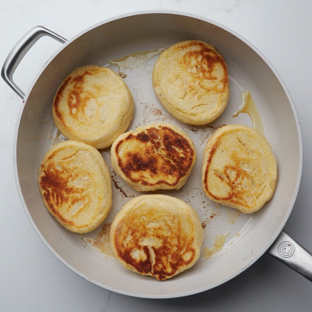 Freshly cooked sourdough English Muffins in a skillet.